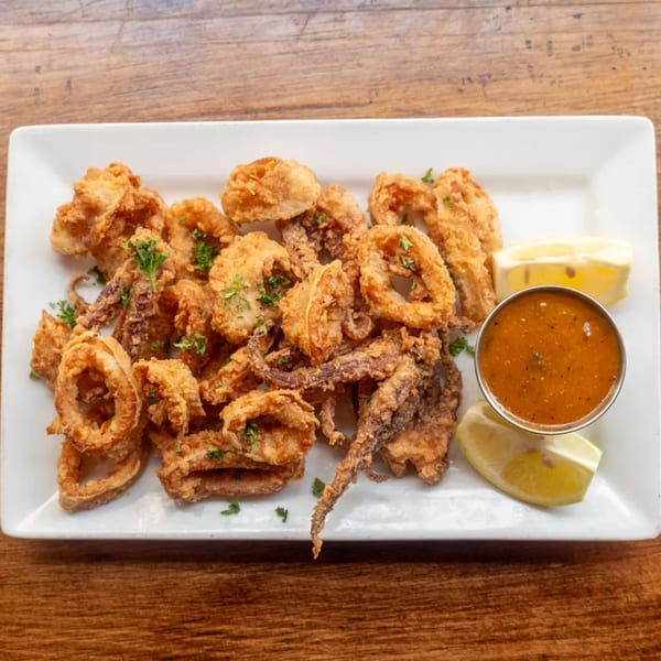 Crispy fried calamari rings and tentacles with parsley, lemon, lime, and a side of dipping sauce.